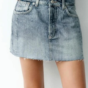 Jeanskjol i blå denim - Trendig jeanskjol i blå denim med klassisk femficksdesign och knappgylf. Perfekt för en avslappnad stil.