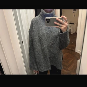 Grå stickad polotröja - Mysig och oversized grå stickad polotröja med lång ärm och hög krage. Perfekt för våren och sommaren enkel att styla till olika outfits till exempel en jeanskjol. Tröjan har en lös passform och är väldigt skön.