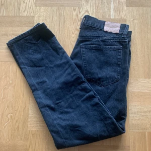 Svarta jeans från weekday  - Snygga mörkblå jeansbyxor från weekday med klassisk femficksdesign och raka ben. Perfekta för dig som gillar en tidlös och enkel stil. Byxorna har bälteshällor och knappstängning i midjan. Modellen heter Barrel.