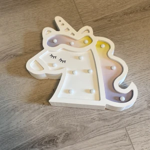 Unicorn nattlampa i plast - Säljer en söt enhörningsformad nattlampa i vit plast med pastellfärgade detaljer. Lampan har små LED-lampor och drivs med batteri. Perfekt som dekoration i barnrummet eller som mysbelysning.