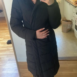 Svart lång dunjacka från 157 - Säljer en svart lång dunjacka från 157 i storlek S. Jackan har lång ärm och är perfekt för kyligare dagar. Klassisk och stilren modell med diskret design och bra längd för extra värme.