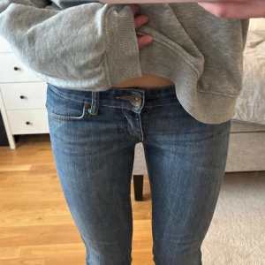 Blå jeansbyxor med normal passform - Säljer ett par klassiska blå jeansbyxor med normal passform och raka ben. Jeansen har fem fickor, knappgylf och subtila slitningar för en tidlös look. Perfekta till vardags och lätta att matcha med olika stilar. Midjemått: 36, Innerbenslängd: 78/80,5 (sprättat eller ej)