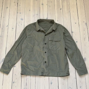 Olivgrön skjorta från Massimo Dutti - Säljer en stilren olivgrön skjorta från Massimo Dutti i 100% bomull. Skjortan har långa ärmar och en bröstficka med knapp. Perfekt för en avslappnad men ändå snygg look.