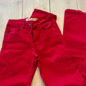 Röda jeansbyxor från Dr. Denim - Säljer ett par snygga röda jeansbyxor från Dr. Denim. Klassisk femficksmodell med dragkedja och knapp framtill. Perfekta för dig som vill sticka ut med färg i vardagen.