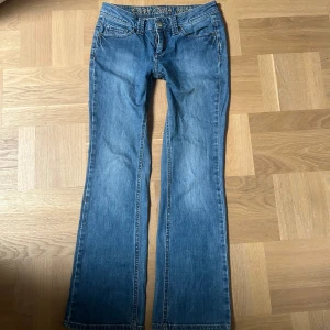 Blå bootcut jeans med broderade bakfickor - Säljer ett par klassiska blå bootcut jeans med snygga broderade detaljer på bakfickorna. Säljer då de är för korta för mig, midjemått: 38cm, innerbenslängden: 74cm. 💓