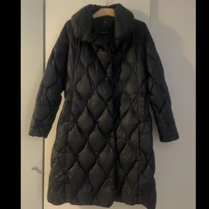 Svart lång quiltad dunjacka - Sparsamt använd jacka från Massimo Dutti. Quiltad lång modell i materialet 80% dun och 20% fjädrar. Dubbelknäppta knappar.           Storlek medium. 