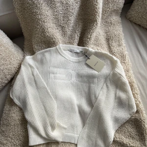Vit stickad tröja från Gestuz - Säljer min helt oanvända topp frản GESTUZ! Strl M, öglestickad. Perfekt tillskott till en capsule wardrobe, styla med en längärmad tröja under för en mer "full" pullover eller med en snygg vit topp Oanvänd, prislapp kvar. Säljer da jag har flera liknande som jag dras mer till!🧵🤍 Materialet är bomull och modellen är lite croppad med avslappnad passform. Nypris 1399kr