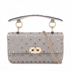 Valentino Rock Studs 2 Way Shoulder Bag - Snygg grå handväska från Valentino Garavani i quiltat skinn med guldiga nitar och kedja. Väskan har ett elegant handtag och avtagbar axelrem i guldfärgad metall. Låset framtill är också i guld och ger en lyxig känsla. Perfekt för dig som gillar statement-accessoarer.