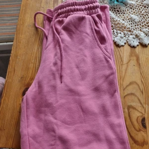 Rosa mjukisbyxor med snörning - Säljer ett par sköna rosa mjukisbyxor med resår och snörning i midjan. Byxorna har sidofickor och är perfekta för en avslappnad stil. Mjukt material som känns bekvämt hela dagen.