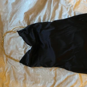 Svart siden klänning  - En klänning som är perfekt för en ute kväll eller utomlands, det är ganska kort och har en slits vid benet även löst vid bröstet och ryggen som man ser på bilden 