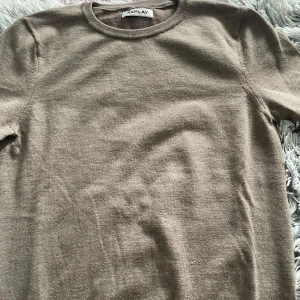 Beige stickad tröja från Replay - En stilren beige stickad tröja från Replay med rund halsringning. Tröjan har en klassisk passform och är perfekt för lager-på-lager. Mjuk och skön känsla, passar till både jeans och chinos.