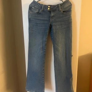 Blå raka jeans från 157 - Klassiska blå jeans från 157 med raka ben i short length. De är låg midja! Jeansen har dubbla guldknappar i midjan och bälteshällor. Perfekta för en avslappnad och stilren look. Tillverkade i jeans material.