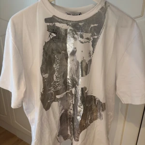 Vit t-shirt med silvrigt tryck från Zara - Vit t-shirt från Zara i bomull med ett stort, abstrakt silvrigt tryck framtill. 💞💞