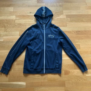 Hugo Boss Hoodie - En Hugo Boss zip hoodie i marinblå färg. Är i fint skick och har inte använts särskilt mycket. Sitter bra och är väldigt skön. Litet slitage på dragkedjan.
