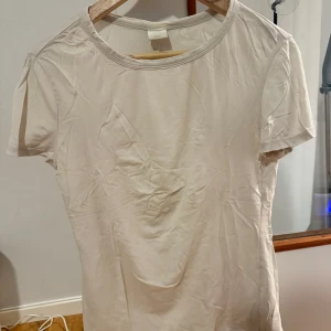 Vit basic t-shirt från H&M - Vit t-shirt från H&M Basics i storlek M. T-shirten har rund halsringning och korta ärmar.