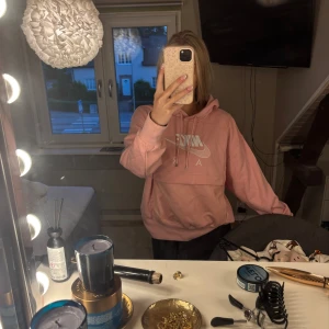 Rosa Nike Air hoodie med logga - Säljer en rosa Nike Air hoodie med stor vit logga framtill. Tröjan har huva med snörning, stor magficka och är långärmad. Mjuk och skön bomullsmix, perfekt för chill dagar eller när du vill ha en sportig vibe.