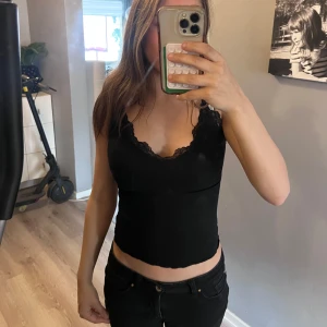 Svart ribbad linnetopp med spets - Svart croppad linnetopp med v-ringning och fina spetsdetaljer längs urringningen. Den är storlek S🖤