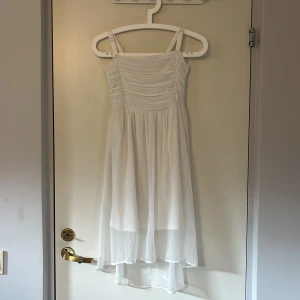 Vit klänning från Lindex, stl 146 - Superfin vit klänning från Lindex i storlek 146. Överdelen har rynkade detaljer och smock i ryggen. Tillverkad i återvunnen polyesterblandning, perfekt för sommarens alla tillfällen. Endast använd en gång så iprincip i nyskick.