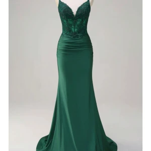 Grön långklänning med spets och pärlor - Snygg lång grön klänning med figurnära passform, djup v-ringning och dekorerad med spets och pärlor upptill. Kjolen är slät och faller elegant mot golvet. Perfekt för bal eller fest. Axelbandslös design och lätt glansigt material. Har andvänts en gång .