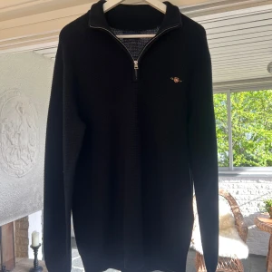 Svart stickad tröja med dragkedja från Gant - Säljer en svart stickad tröja från Gant med halv dragkedja och liten broderad logga på bröstet. Storlek M men kan även passa en större storlek. Nytt pris 1700 kr, mitt pris 500 kr✅ 