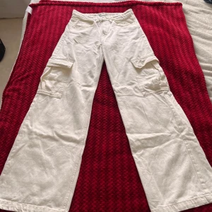 Vita cargopants med vida ben - Säljer ett par vita cargopants med bred passform och stora fickor på sidorna. Byxorna har normal midja och raka, vida ben. Perfekta för en avslappnad och trendig stil. Byxorna har ej kvar prislapp men är helt oanvända 💕