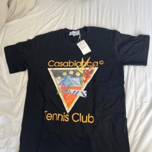 Svart t-shirt från Casablanca - Säljer en svart t-shirt från Casablanca Tennis Club med färgglatt grafiskt tryck framtill. T-shirten är i storlek M och aldrig använd