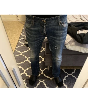 Blå Dsquared2 jeans med slitningar - Säljer ett par blå jeans från Dsquared2 med tydliga slitningar på framsidan. Jeansen har klassisk femficksdesign, raka ben och läderpatch med logga bak. Snygg tvätt och detaljer som ger en cool, använd look…Priset går självklart att diskutera!