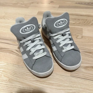 Grå Adidas sneakers med vita ränder - Säljer ett par grå Adidas campus som inte längre kommer till användning. Har använt det fåtal gånger pga det inte är mina favorit skor längre. Det finns lite smuts men går att ta bort ! Skosnöret är sjävlgjora, så om du vill göra om det så går det! Ord. pris 1600 från MerchSweden. BILDER FRÅN MIN VINTED !!