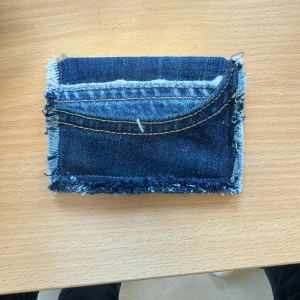 Handgjord plånbok i jeans - Unik plånbok sydd av återvunnet jeanstyg med råa kanter och en synlig ficka på framsidan. Perfekt för kort och småsaker. Den har en cool, avslappnad stil och är lätt att bära med sig.