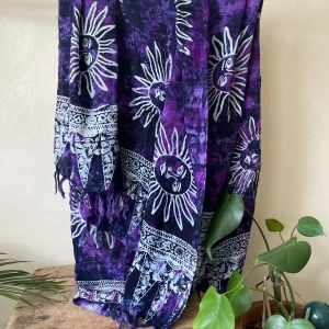 Batikfärgad sarong med solar - Helt oanvänd batikfärgad sarong i lila och marinblått med vida solar och mönster. Perfekt för dig som vill ha något unikt till stranden.