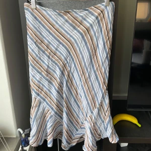 Randig kjol från Café Théâtre - Säljer en snygg kjol från Café Théâtre med diagonala ränder i blått, brunt och vitt. Kjolen har volang nertill!!