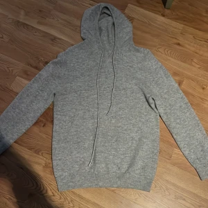 Grå hoodie i merino ull/kashmir - Säljer en enkel och stilren grå hoodie med huva och dragsnören.