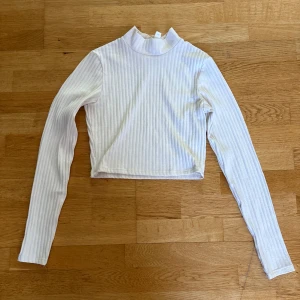 Vit ribbad croppad polotopp - Vit ribbad polotopp från H&M. Toppen har långa ärmar och en hög krage.