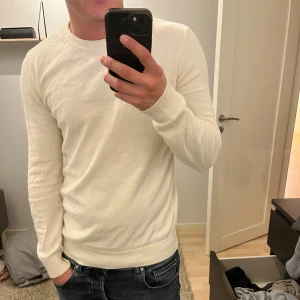 Vit stickad tröja från H&M - Säljer en stilren vit stickad tröja från H&M i slim fit-modell. Säljer på grund av att den inte kommer till användning.