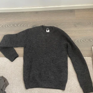 Mörkgrå stickad tröja från A.P.C. - Säljer en stilren mörkgrå stickad tröja från A.P.C. med rund halsringning. Perfekt för lager-på-lager och enkel att matcha med olika outfits. Klassisk modell med lång ärm och mjukt material. Knappt använd. Storlek: S Skick:8/10