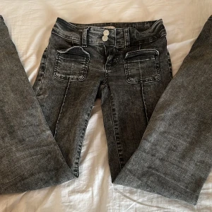 Grå jeansbyxor med vida ben från Nelly - Säljer ett par bekväma lågmidjade gråa jeansbyxor från Nelly (just denna färg finns inte längre att köpa på deras hemsida) med utsvängda ben och markerade sömmar. Byxorna har två stora fickor framtill, dubbla knappar i midjan och dragkedja. Perfekta för dig som gillar en avslappnad men trendig stil. De är i storlek XS/34, men passar även för storlek S för att de är väldigt stretchiga runt midjan. 💕