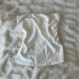 Vit tubtopp från Stradivarius - Säljer en enkel och stilren vit tubtopp från Stradivarius. Toppen är ärmlös och har en rak passform, perfekt att matcha med jeans eller kjol. Tillverkad i mjuk bomull för en bekväm känsla.