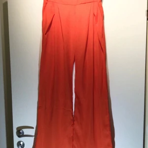 Vida röda byxor med hög midja - Märkta som L, men är små i storlek Lätta och tunna med 2 sidfickor fram Dold dragkedja bak Oanvända Beninnerlängd: 77 cm