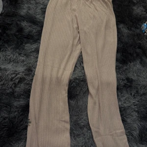 Beige ribbade byxor med utsvängda ben - Säljer ett par beige ribbade byxor med utsvängda ben och resår i midjan. Byxorna har en mjuk och bekväm känsla, perfekta för en avslappnad stil. Passar bra till både sneakers och boots.