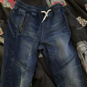 Tja säljer ett par mörk blåa jeans byxor med snöre från jogger&denim - Säljer ett par mörk blåa jeans från jogger&denim. Har aldrig använt de för de är för små för mig. Inga hål eller märken, storlek 158 12-13y midja vet ej vilken storlek. Inga tecken på användning. Pris kan diskuteras