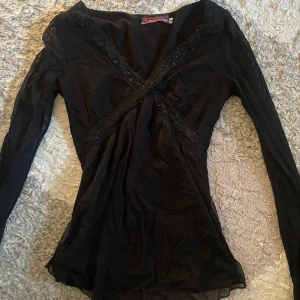 Svart blus - Svart blus med detaljer runt bröstkorgen, använt några gånger. Finns några små trådar som sticker ut 