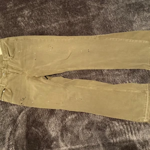 Zara flared jeans - Säljer ett par beiga jeansbyxor med flared ben. Byxorna har små färgstänk som ger en unik look. Passar perfekt till en avslappnad stil och är lätta att matcha med olika överdelar. Använda en gång, 10/10 skick.