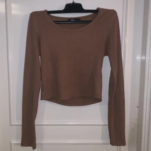 Brun ribbad croppad långärmad topp från FB Sister - Säljer en brun ribbad croppad långärmad topp från FB Sister. Toppen har en rund halsringning och är tillverkad i ett mjukt material som sitter snyggt på kroppen. Perfekt att styla med jeans eller kjol!