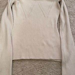 Beige ribbad långärmad tröja H&M - Superfin beige ribbad tröja från H&M med lång ärm och snygga V-detaljer framtill. Tröjan har en tight passform och är perfekt att styla med jeans eller kjol. Mjuk och stretchig, passar både till lager-på-lager och som den är.