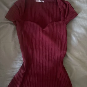 Vinröd ribbad kortklänning Anna Field - Säljer en vinröd ribbad kortklänning från Anna Field. Klänningen har korta ärmar, figurnära passform och en snygg v-ringad sweetheart-urringning. Perfekt för dig som gillar stilrena och trendiga plagg med lite edge.