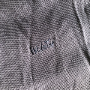 Mörkblå pikétröja från Wolsey - Snygg mörkblå pikétröja från Wolsey med klassisk krage och korta ärmar. Tröjan har diskret broderad logga på bröstet och är gjord i mjuk bomull som känns skön mot huden. Perfekt för en avslappnad och stilren look.