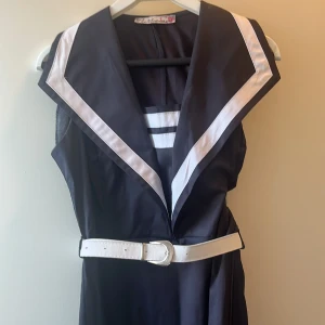 Marinblå klänning med vit krage Matmazel - Snygg marinblå klänning från Matmazel med bred vit krage och matchande vit bälte i midjan. Ärmlös modell med coola ränder vid halsen som ger sailor-vibes. Perfekt för dig som vill sticka ut med en klassisk men unik look.