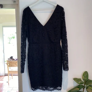 Svart spetsklänning Vero Moda  - Svart klänning från Vero Moda med långärmade ärmar och v-ringad hals. Klänningen är täckt av spets och ser lika dan ut på både framsidan och baksidan.
