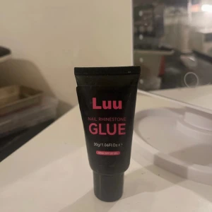 Luu Nail Rhinestone Glue - Luu Nail Rhinestone Glue är ett svart tub med lim för att fästa nageldekorationer som stenar. Tuben innehåller 30g och är perfekt för kreativa nageldesigner. Limmet är UV-gel och kan enkelt tas bort genom att blötläggas.