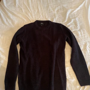 Svart stickad tröja från Clockhouse - Mysig svart stickad tröja från Clockhouse i storlek M. Tröjan har en rund halsringning, långärmade ärmar och ett diskret stickat mönster. Perfekt för kyliga dagar och enkel att matcha med jeans eller kjol.